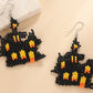 A pair of black, orange, and yellow beaded Halloween-themed haunted house earrings.
