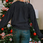 Woman in a black round neck sweatshirt and jeans, facing away from the camera.