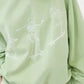 A light green oversized sweatshirt features three white skeleton graphics skateboarding.