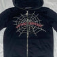 Black zip-up hoodie with a rhinestone spider web design and "UNFINISHEDDREAMZ" text.