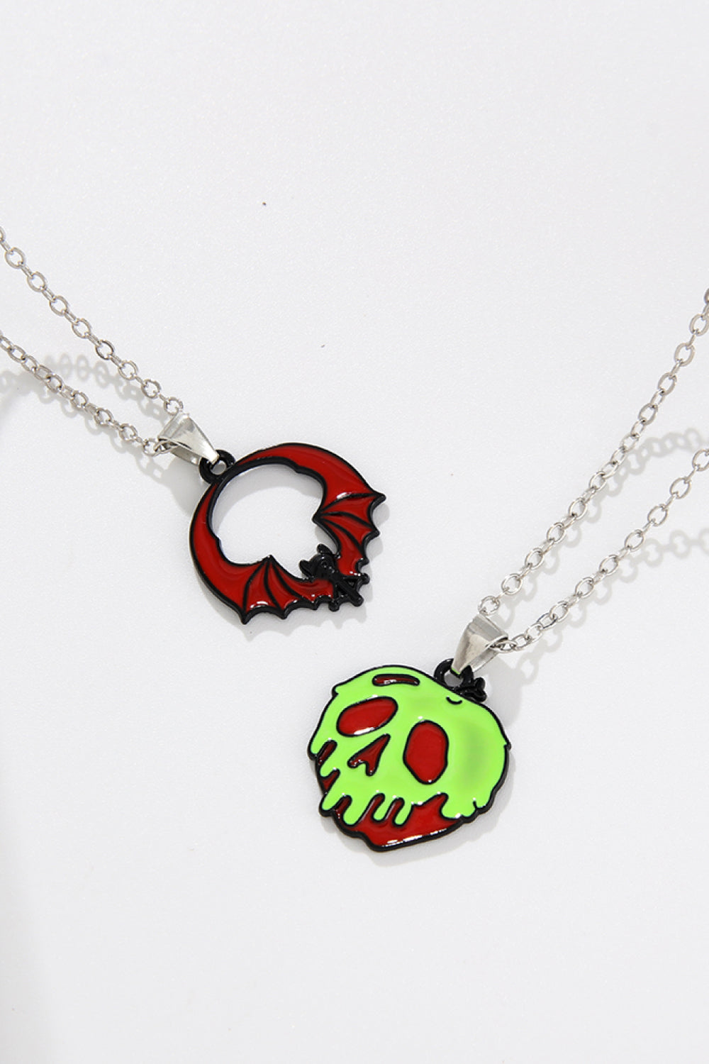 Two Halloween-themed necklaces, one with a red bat and the other a green skull.