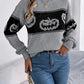 Gray long-sleeve sweater with black pumpkin pattern and blue jeans.