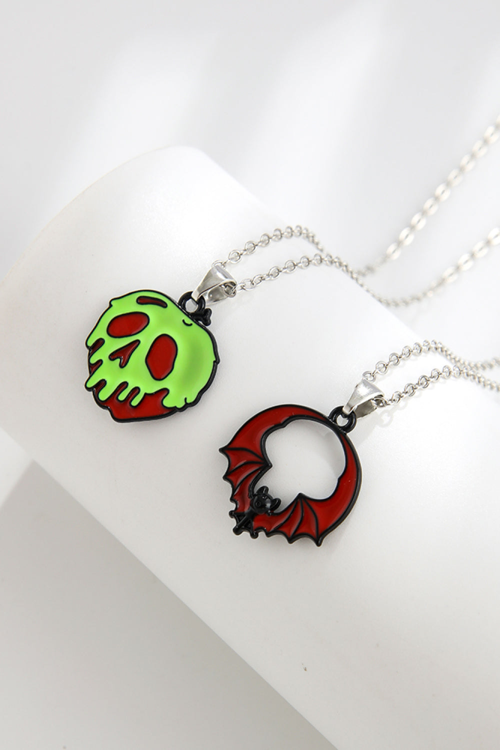 Two Halloween-themed necklaces, one with a green skull and one with a red bat.