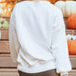 White long sleeve sweatshirt with a Halloween pumpkin patched pattern.