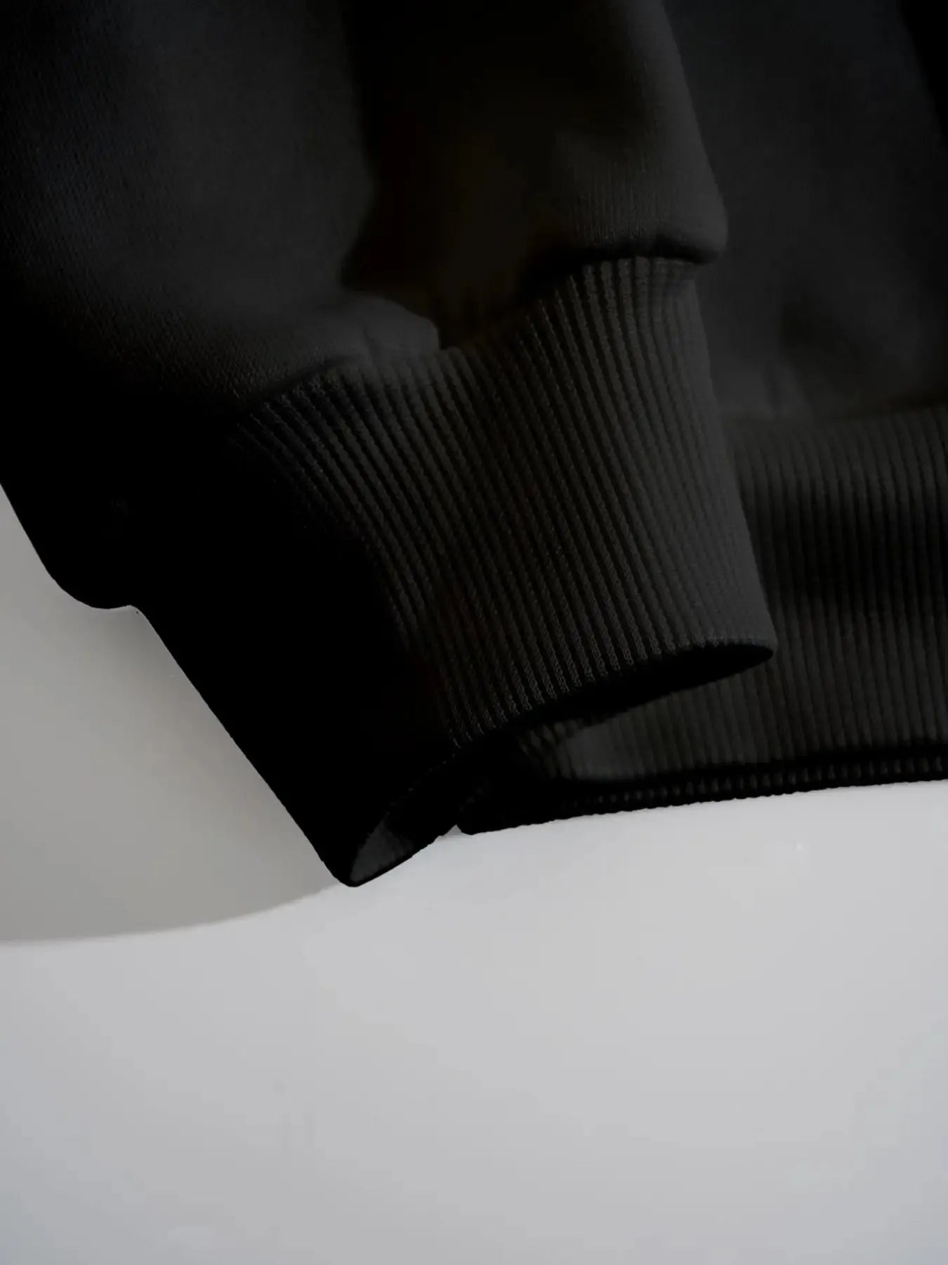 Close-up of a black sweatshirt sleeve and ribbed cuff.