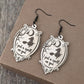 A pair of wooden dangle earrings featuring a witch on a broomstick and the phrase "I put a spell on you."