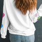 A woman from behind wears a white long-sleeve sweatshirt with colorful pumpkin designs.