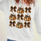 A woman wears a white long-sleeve sweatshirt with a pumpkin and leopard print bow graphic.