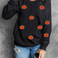 Black long-sleeve sweatshirt with sequin pumpkin appliques.