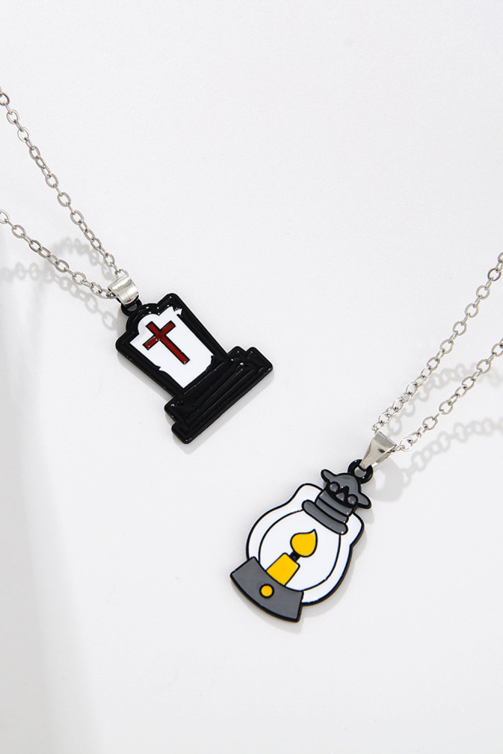 Two necklaces, one with a tombstone pendant and one with a lantern pendant.
