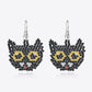 A pair of black beaded cat-face earrings with yellow eyes and a red nose.