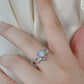 A silver bat ring with a moonstone center is worn on a finger.
