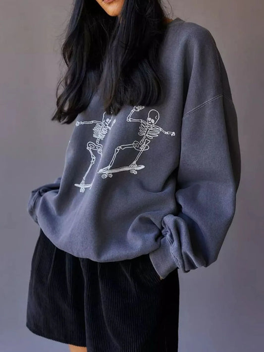 Oversized gray sweatshirt with a white graphic of two skeletons skateboarding.