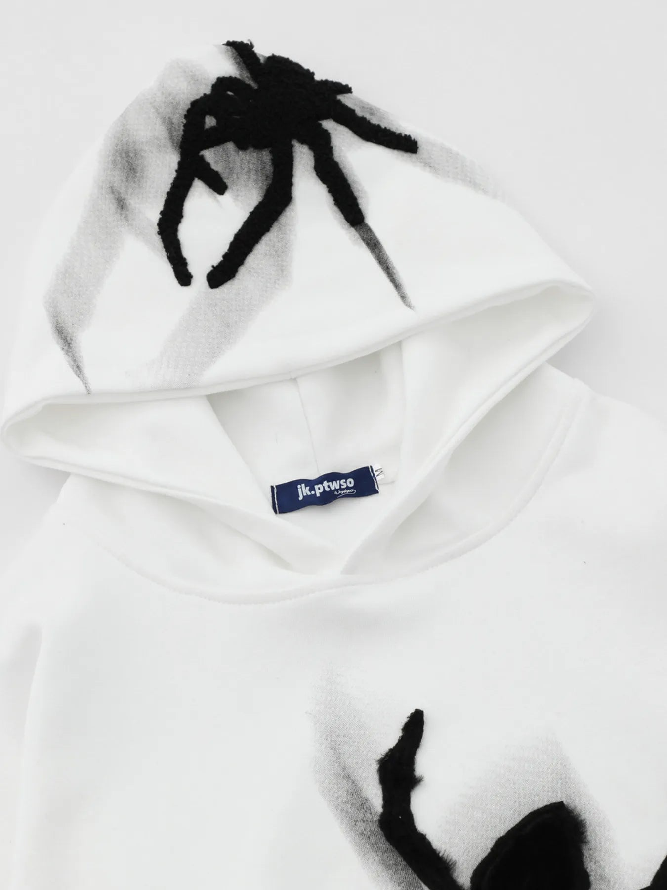 White men's oversized hoodie with a black spider graphic on the hood and front.