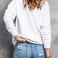 A woman from behind wears a white round neck sweatshirt and distressed jeans.