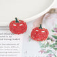 A pair of red rhinestone pumpkin earrings with a jack-o'-lantern face.