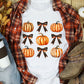A white short-sleeve t-shirt with pumpkin and Halloween bow graphics.