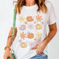 A woman wears a white short-sleeve t-shirt with pumpkin and flower graphics.