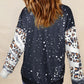 A woman from behind wears a black sweatshirt with white paint splatters and leopard print sleeves.
