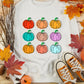 A white long-sleeve sweatshirt features nine colorful pumpkin graphics.