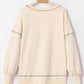 Cream sweatshirt with colorful contrast stitching on the neckline, sleeves, and hem.
