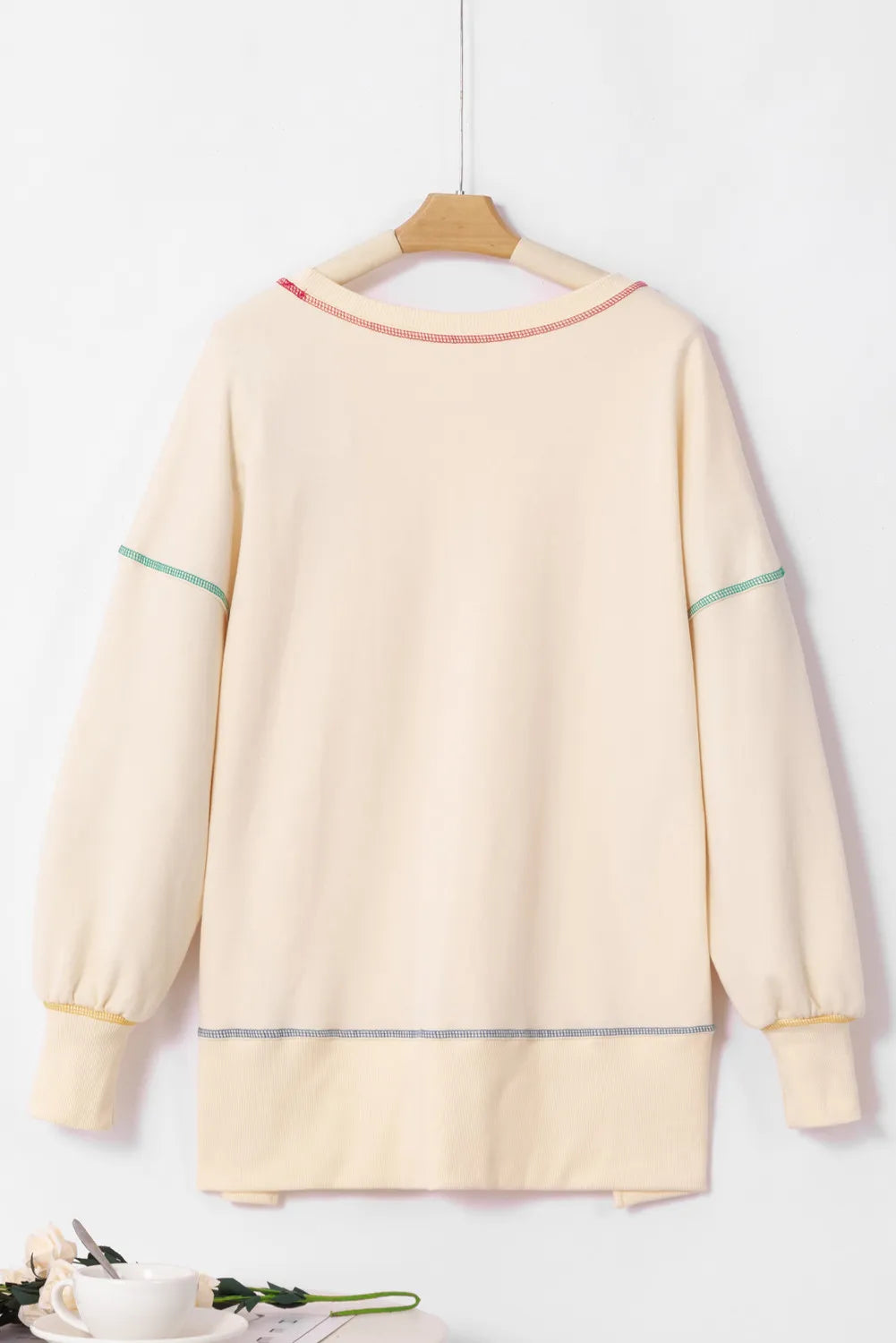 Cream sweatshirt with colorful contrast stitching on the neckline, sleeves, and hem.