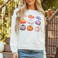 A woman wears a white long-sleeve sweatshirt with a colorful pumpkin graphic.