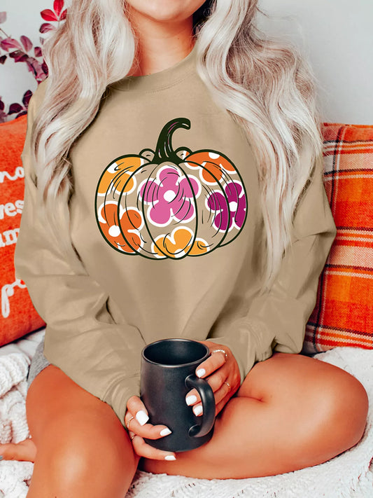 A woman wears a beige drop shoulder sweatshirt with a floral pumpkin graphic.