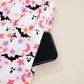 Pink Halloween ghost print pants with a phone in the pocket.