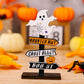 A wooden Halloween signpost with a ghost on top and three directional arrows.